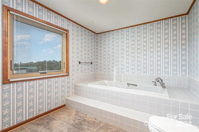 bathroom featuring tile patterned flooring, toilet, crown molding, and tiled tub