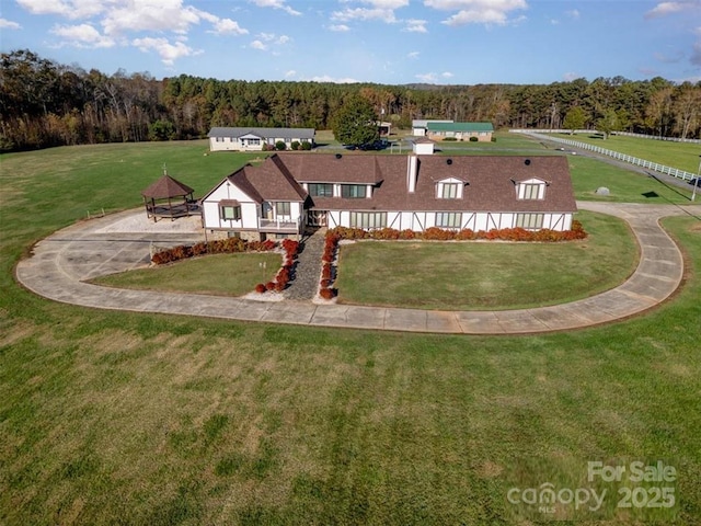 view of front of house featuring a forest view and a front lawn