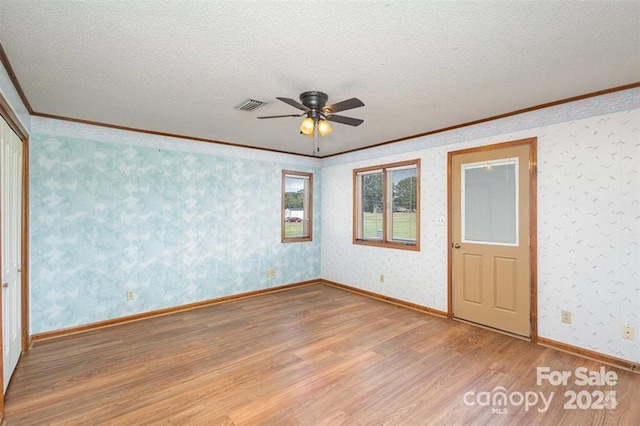 unfurnished room with wallpapered walls, a textured ceiling, visible vents, and light wood-style floors