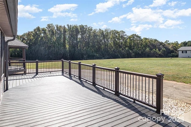 wooden deck featuring a lawn and a wooded view