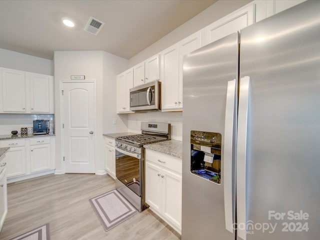 kitchen with tasteful backsplash, light stone counters, light hardwood / wood-style floors, and appliances with stainless steel finishes