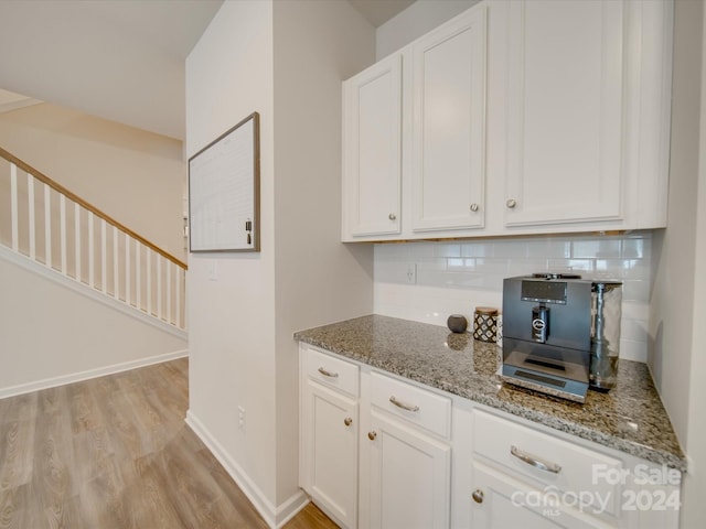 kitchen featuring white cabinets, light stone counters, backsplash, and light hardwood / wood-style flooring