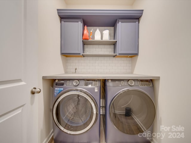 clothes washing area featuring washer and clothes dryer and cabinets