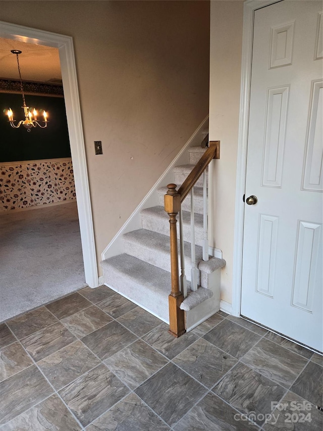 stairs with carpet floors and a chandelier