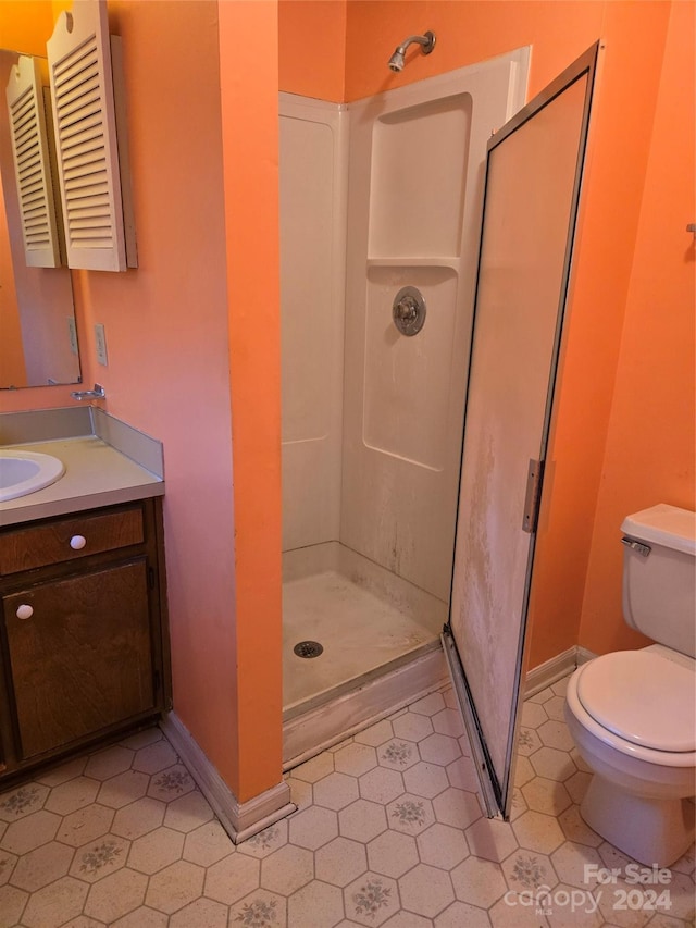 bathroom featuring tile patterned flooring, toilet, vanity, and walk in shower