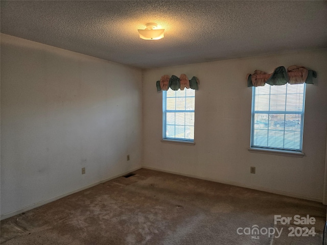 unfurnished room featuring carpet flooring and a textured ceiling