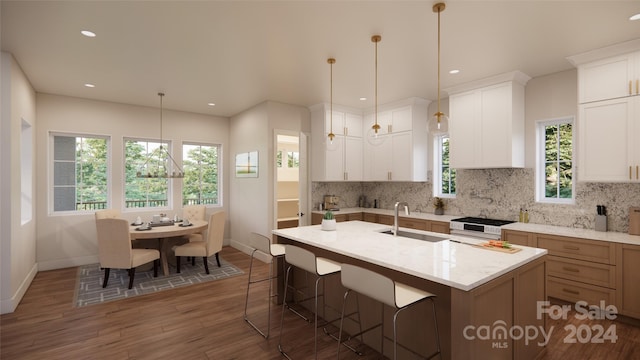 kitchen with dark hardwood / wood-style floors, white cabinetry, a wealth of natural light, and a center island with sink