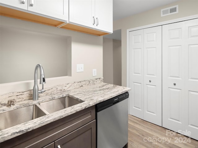 kitchen with dishwasher, sink, light stone counters, white cabinets, and light wood-type flooring