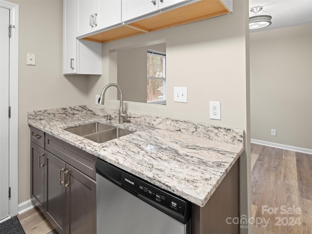 kitchen with white cabinetry, dishwasher, sink, light stone counters, and light hardwood / wood-style flooring