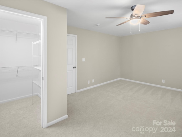 unfurnished bedroom featuring ceiling fan, light colored carpet, and a closet