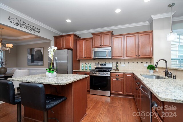 kitchen with a kitchen breakfast bar, sink, appliances with stainless steel finishes, decorative light fixtures, and kitchen peninsula