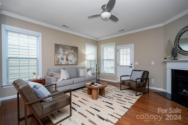 living room with a wealth of natural light, hardwood / wood-style floors, and crown molding