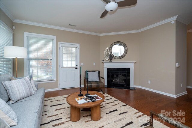 living room featuring dark hardwood / wood-style flooring, ceiling fan, and crown molding