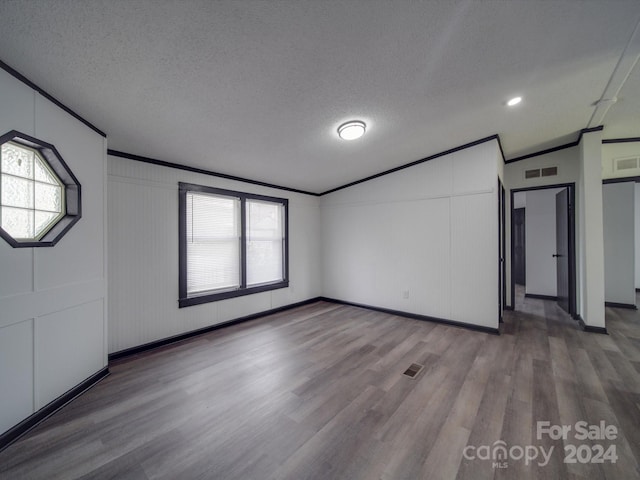 spare room with lofted ceiling, wood-type flooring, a textured ceiling, and ornamental molding