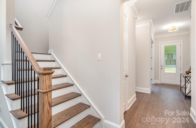 stairway with wood-type flooring and ornamental molding