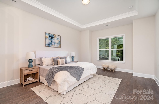 bedroom featuring a raised ceiling, dark wood-type flooring, and crown molding