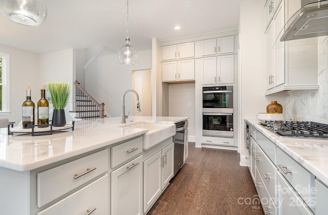 kitchen featuring wall chimney exhaust hood, a sink, white cabinetry, and stainless steel appliances