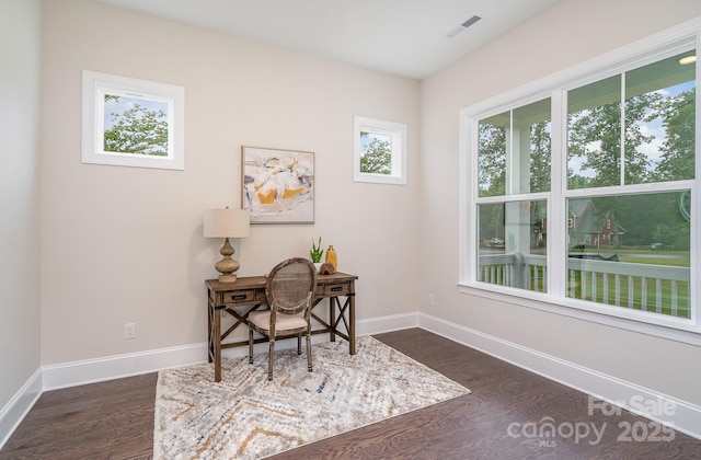 home office with dark wood-style flooring, plenty of natural light, and baseboards