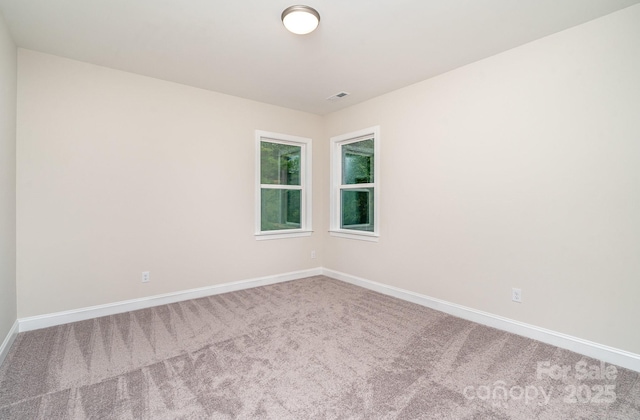 unfurnished room with carpet flooring, visible vents, and baseboards