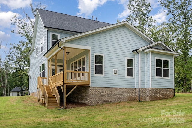 rear view of property featuring brick siding, roof with shingles, stairway, and a yard