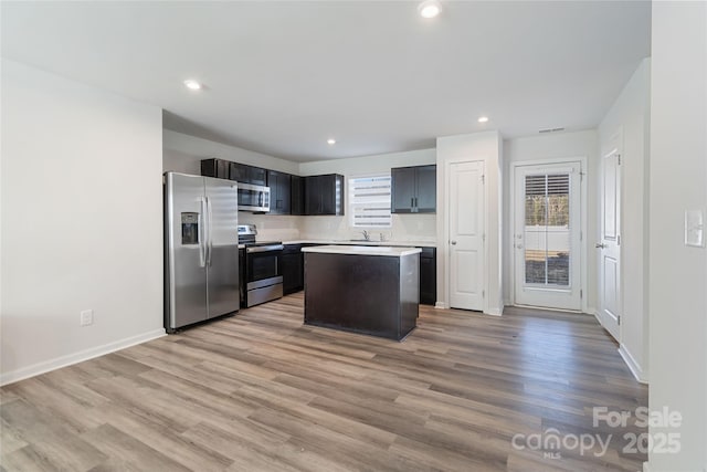 kitchen featuring sink, a kitchen island, stainless steel appliances, and light hardwood / wood-style floors