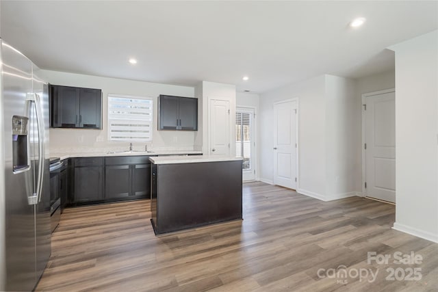 kitchen with a healthy amount of sunlight, hardwood / wood-style floors, a kitchen island, and stainless steel appliances