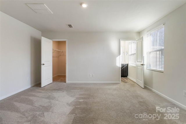 unfurnished bedroom with light colored carpet, a spacious closet, and a closet