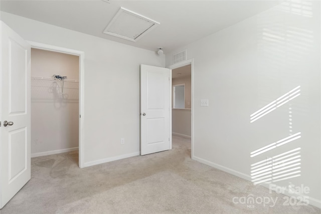 unfurnished bedroom featuring a walk in closet, light carpet, and a closet