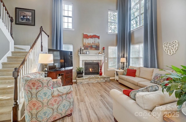 living room featuring a fireplace, a towering ceiling, hardwood / wood-style flooring, and plenty of natural light