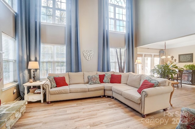 living room with light wood-type flooring, a high ceiling, and a chandelier