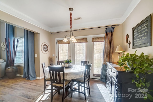 dining area featuring a chandelier, dark hardwood / wood-style floors, and crown molding