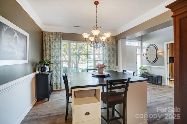 dining space with a notable chandelier, wood-type flooring, and ornamental molding