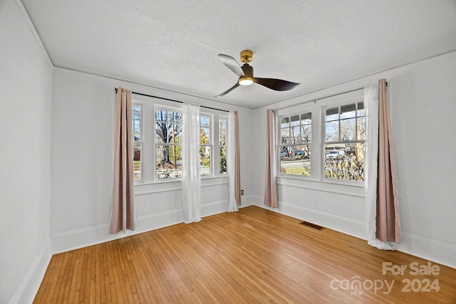 spare room with hardwood / wood-style flooring, ceiling fan, and a textured ceiling