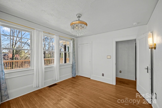 interior space with a notable chandelier, wood-type flooring, and a textured ceiling