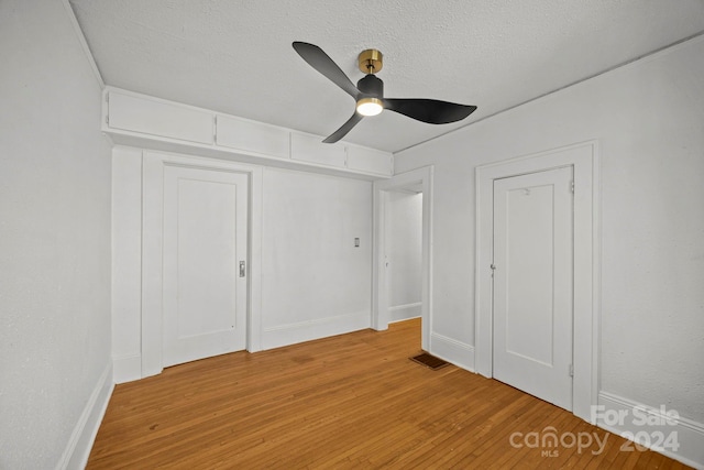 unfurnished bedroom with a textured ceiling, light wood-type flooring, and ceiling fan