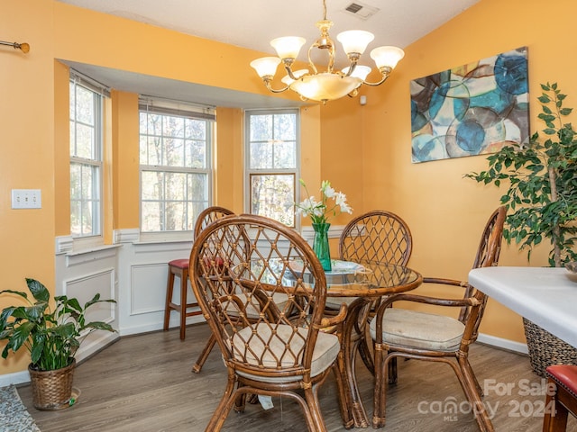 dining area with wood-type flooring and an inviting chandelier