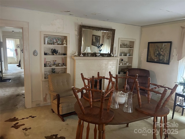 interior space featuring built in shelves, a fireplace, and light carpet