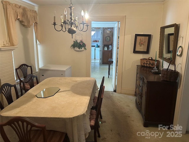 dining room with light colored carpet, washer / dryer, ornamental molding, and a chandelier