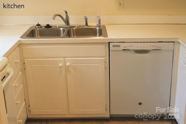 kitchen with white dishwasher, white cabinets, and sink