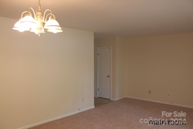 carpeted empty room with a notable chandelier