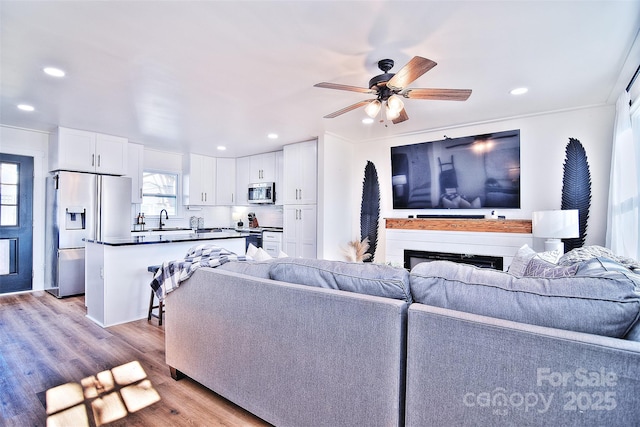 living room with light hardwood / wood-style floors, ceiling fan, and sink