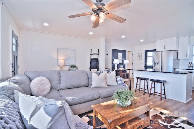 living room featuring ceiling fan, light wood-type flooring, and ornamental molding