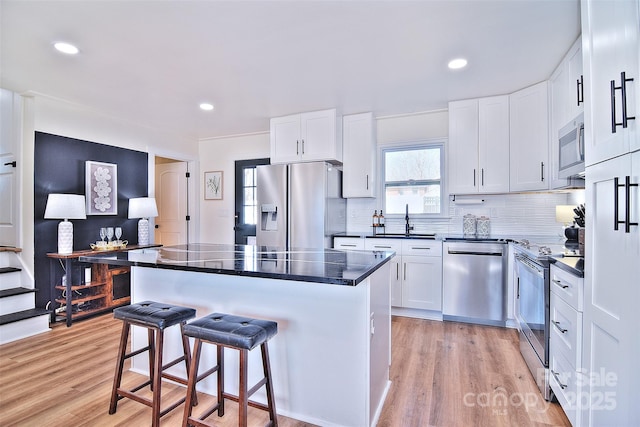 kitchen featuring a kitchen breakfast bar, a center island, white cabinetry, and stainless steel appliances