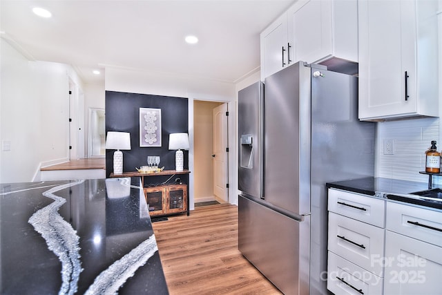 kitchen featuring backsplash, stainless steel fridge, light hardwood / wood-style flooring, and white cabinets