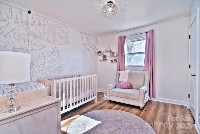 bedroom featuring a crib, crown molding, and dark hardwood / wood-style floors