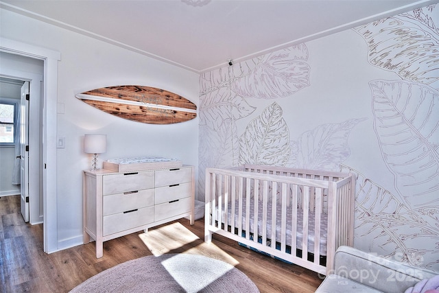 bedroom featuring a crib and dark hardwood / wood-style flooring