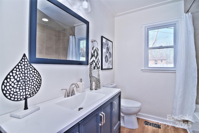 bathroom featuring wood-type flooring, vanity, toilet, and walk in shower