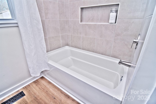 bathroom featuring hardwood / wood-style flooring and shower / bath combo with shower curtain