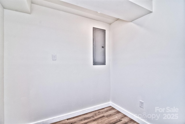 unfurnished room featuring electric panel and hardwood / wood-style flooring