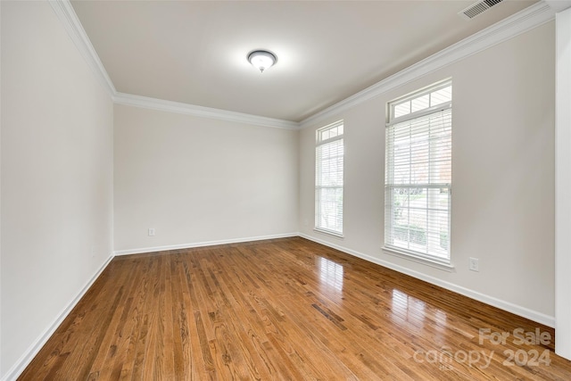 empty room featuring hardwood / wood-style floors and crown molding